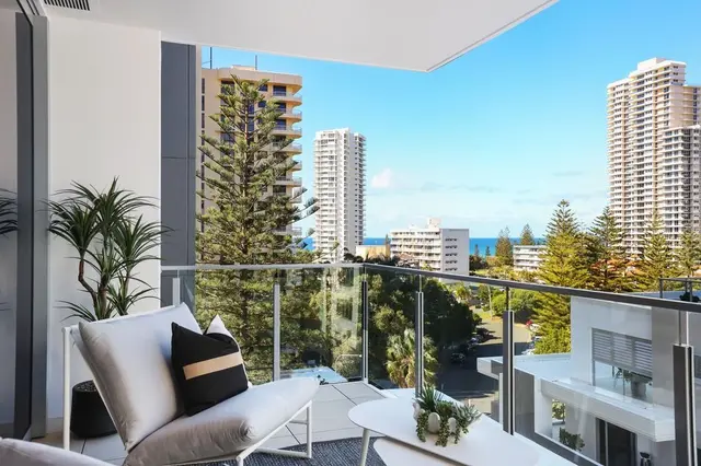 Balcony with white outdoor lounge, striped cushion and views to high-rises and ocean