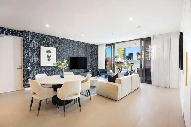 Open-plan living and dining with navy patterned feature wall, round marble table and boucle chairs