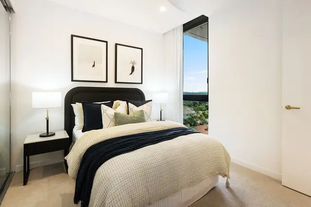 Bedroom with black bedhead, cream waffle bedding, navy throw and framed figure prints