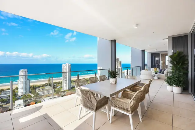 Wraparound balcony with concrete dining table, woven rope chairs and sweeping beachfront ocean views