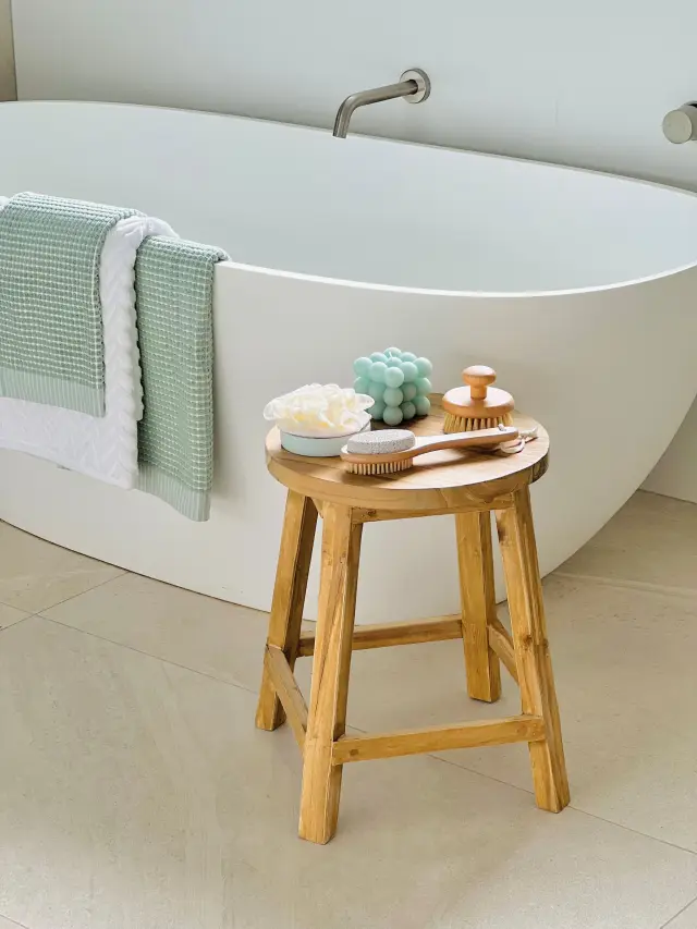 Freestanding bathtub with timber stool, sage waffle towel and bath accessories