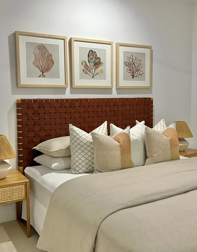 Third bedroom with woven leather bedhead, coral artwork triptych and linen bedding