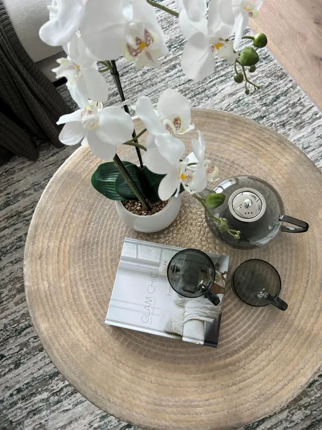 Hammered brass drum table with white orchid, green tea set and design book