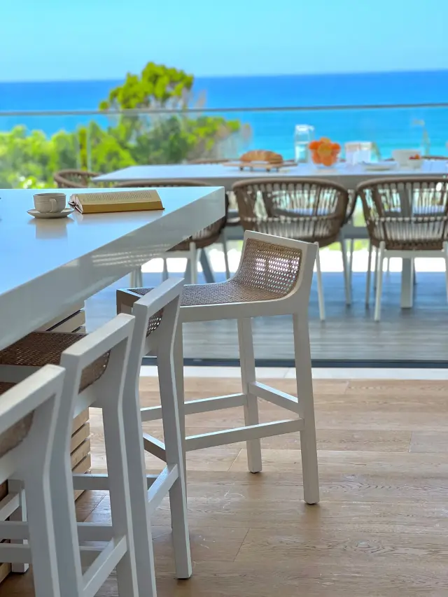 Kitchen bar with white woven stools overlooking ocean views and outdoor dining terrace