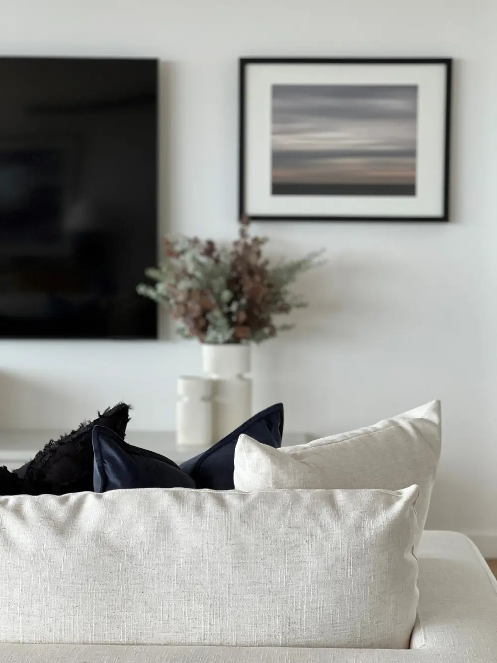Living room detail with cream linen sofa, navy cushions and abstract seascape print