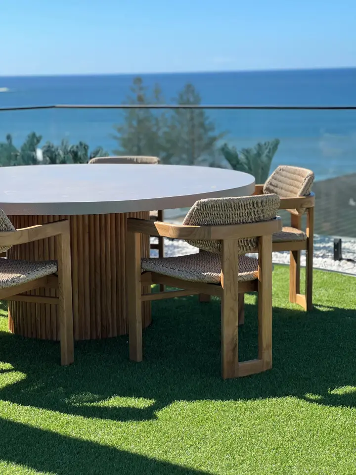 Rooftop dining with round concrete table, rope-woven teak chairs and ocean views