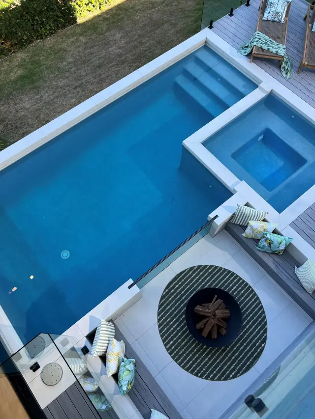 Aerial view of resort-style pool with integrated spa, fire pit lounge and timber sun loungers