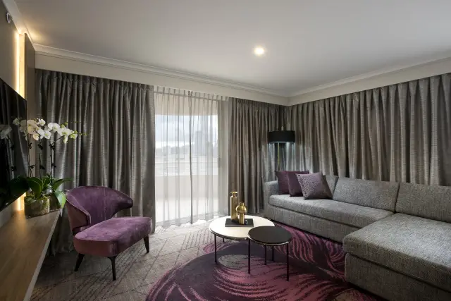 Suite lounge with modular grey sofa, velvet accent chair and nested marble side tables