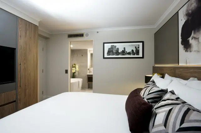 Guest room with ensuite freestanding bathtub, framed skyline print and timber wardrobe