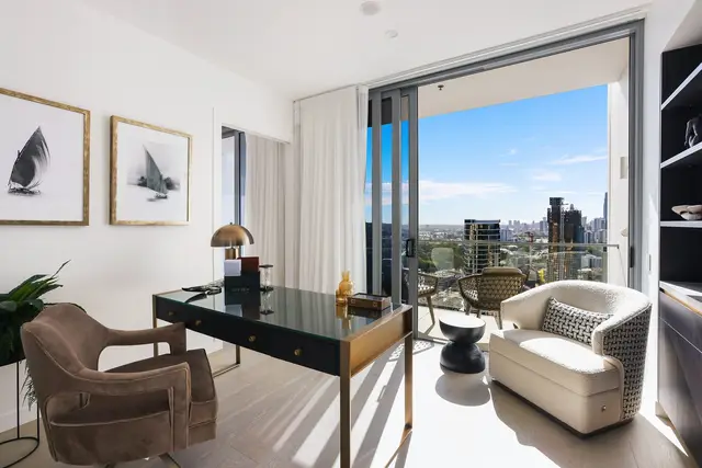 Study with black-and-brass desk, tan suede chair, cream boucle armchair and city skyline outlook