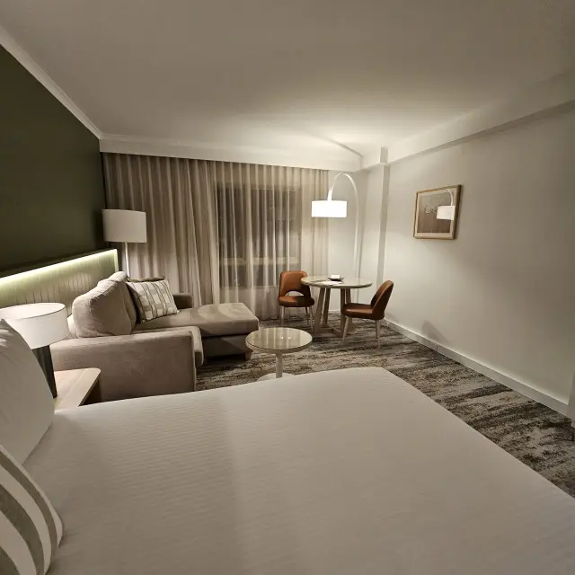 Suite living area with a modular sofa, round dining table and tan leather dining chairs beside a framed artwork