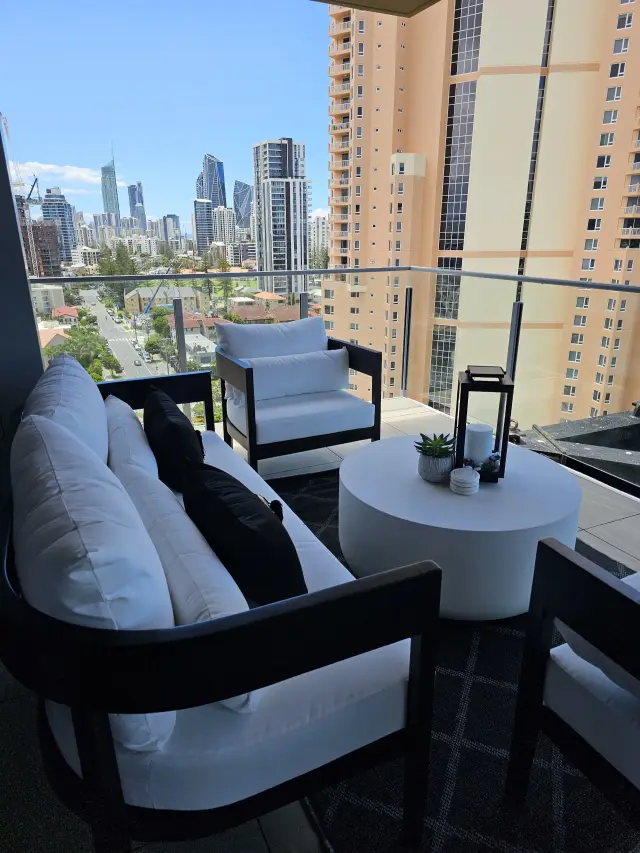 Balcony lounge with white sofa, black-framed chairs and Gold Coast high-rise views