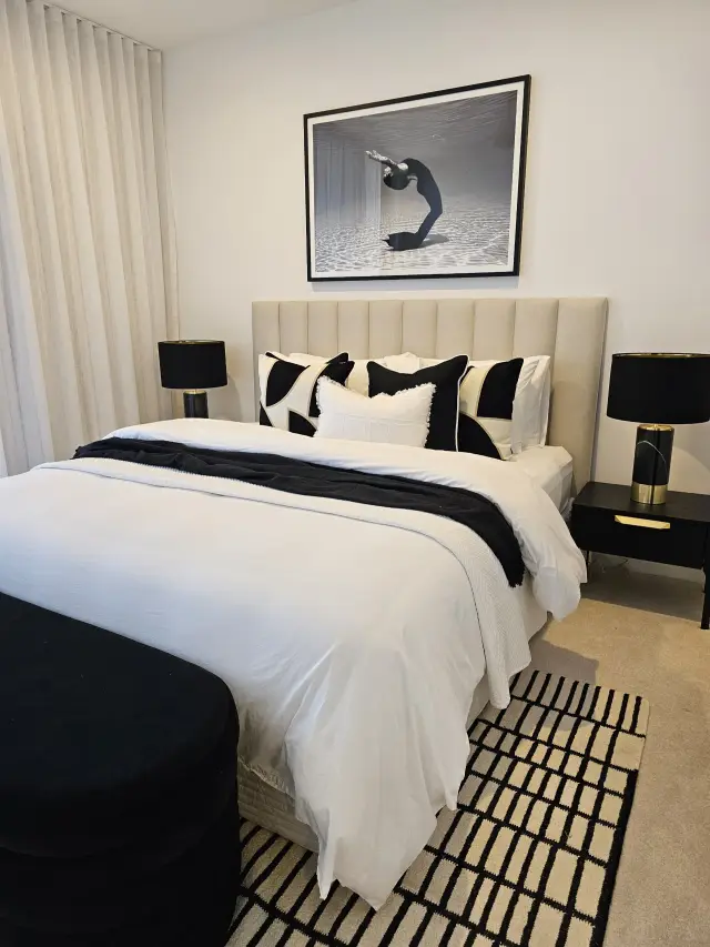 Guest bedroom with beige bedhead, black-and-white cushions and underwater dancer photograph