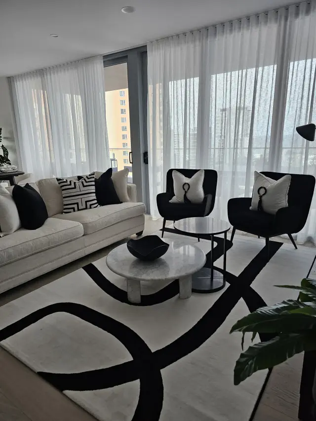 Living room with cream sofa, black velvet armchairs and bold black-and-white curved rug