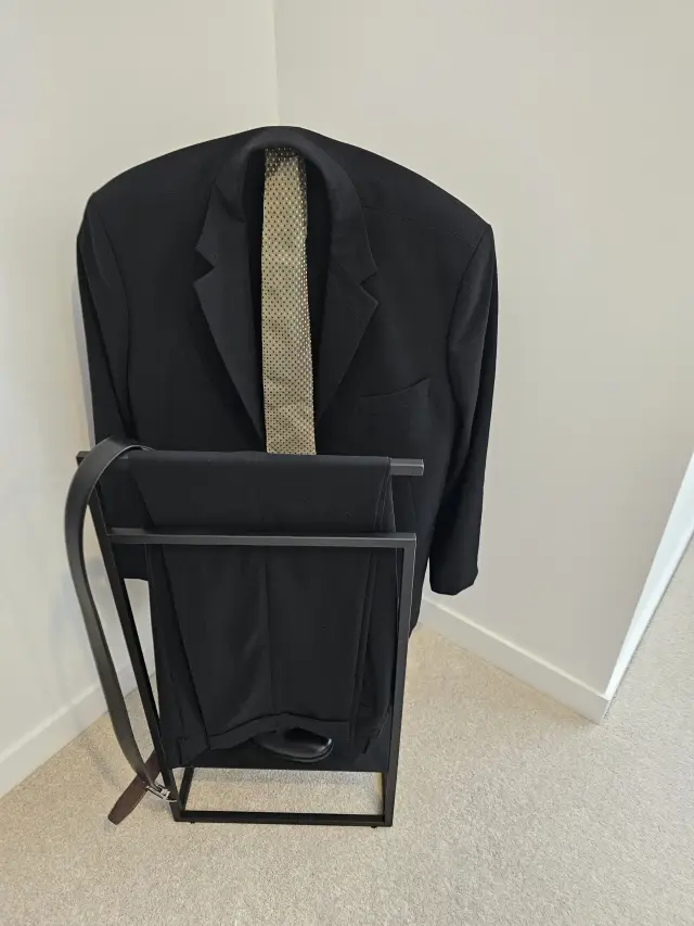 Black suit jacket, tie and trousers styled on a black timber valet stand