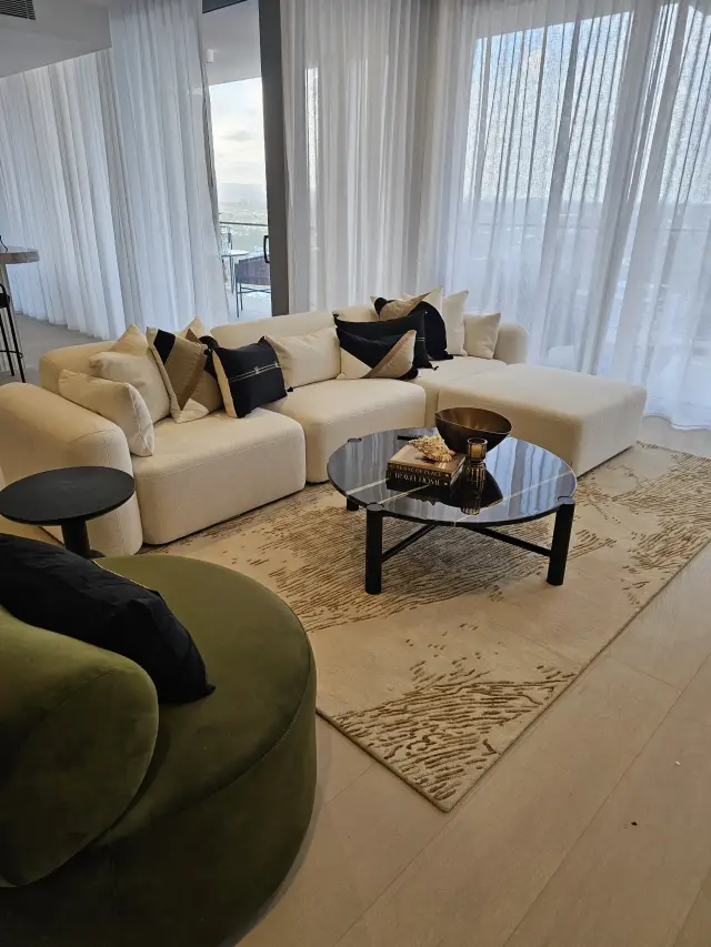 Living room with cream modular sofa, black glass coffee table and olive velvet swivel chair