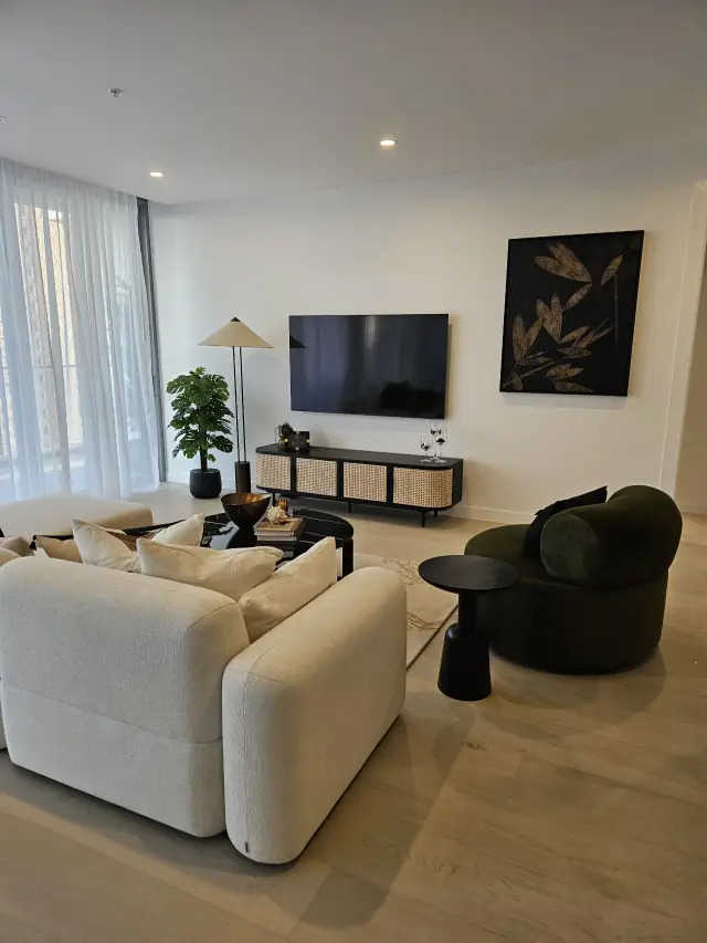 Living room with cream sofa, rattan media console, olive velvet chair and botanical artwork