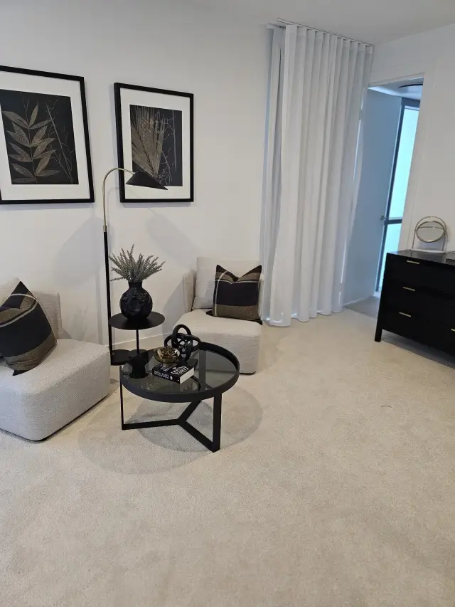 Sitting room with grey armchairs, glass coffee table, botanical prints and black dresser