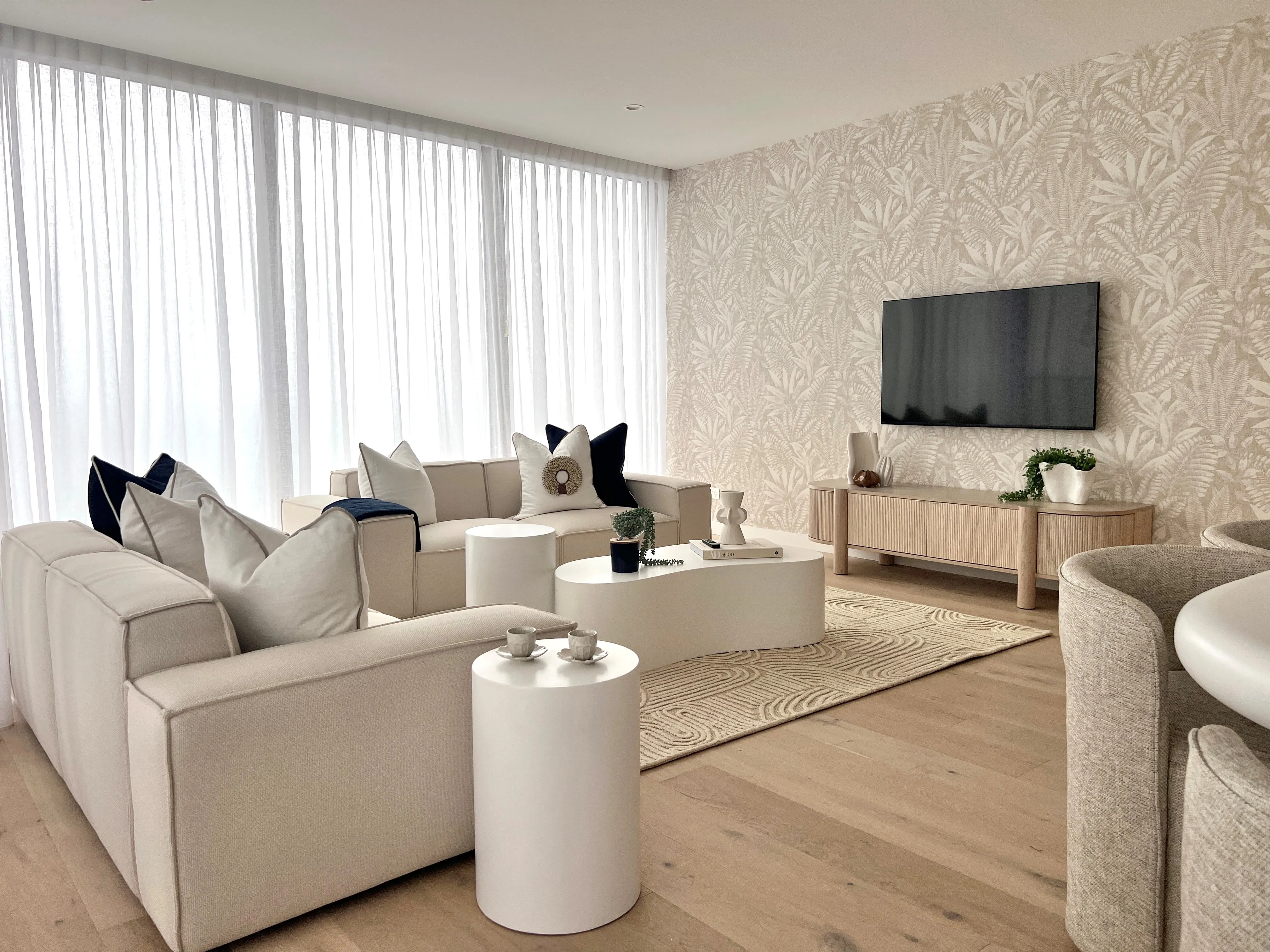 Dawn Broadbeach living room with botanical wallpaper, cream sofas and oak entertainment unit