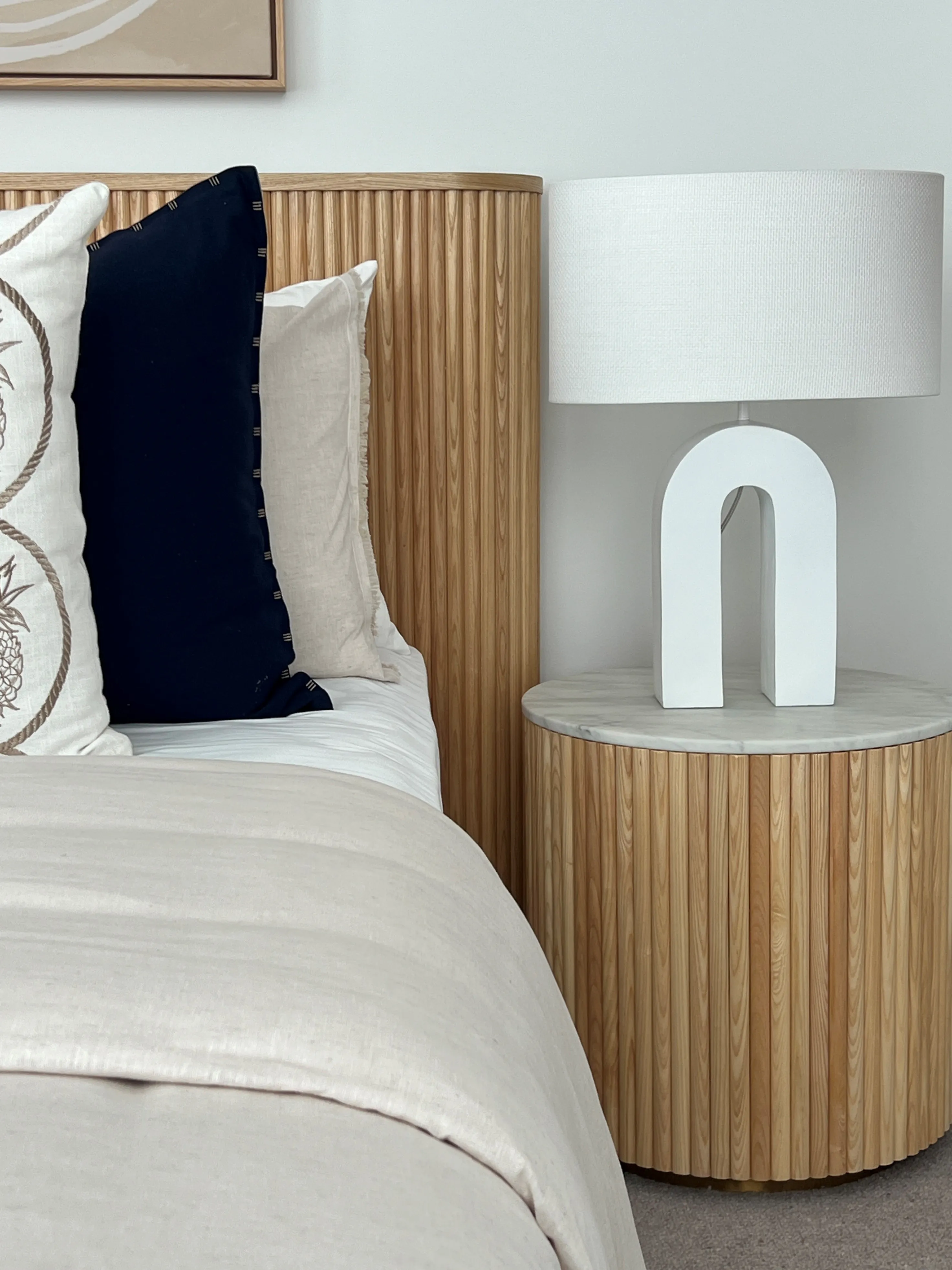 Master bedroom with fluted oak bedhead, arch lamp and marble-top bedside table