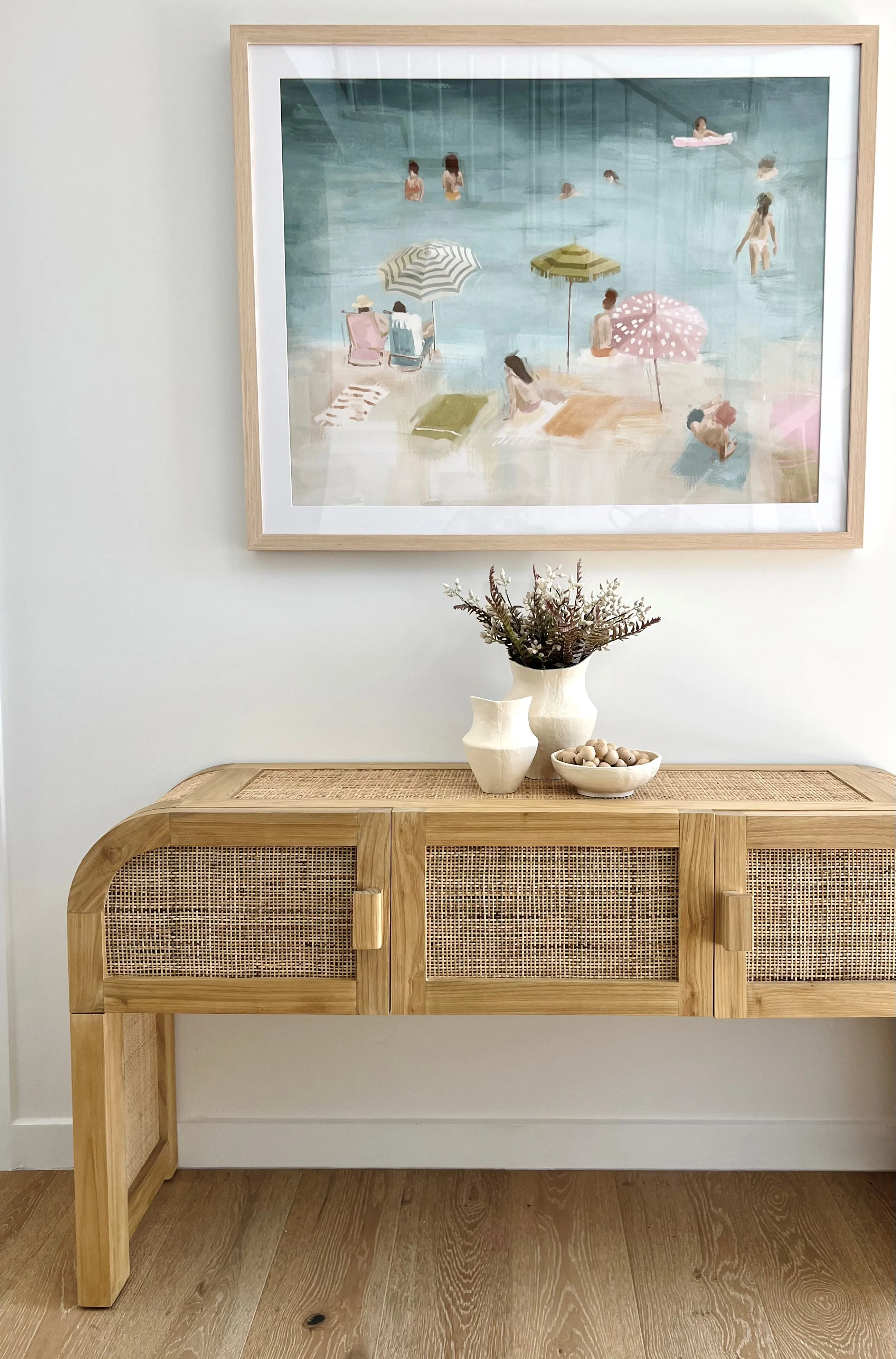 Entry console in rattan and cane with coastal beach scene artwork and woven basket