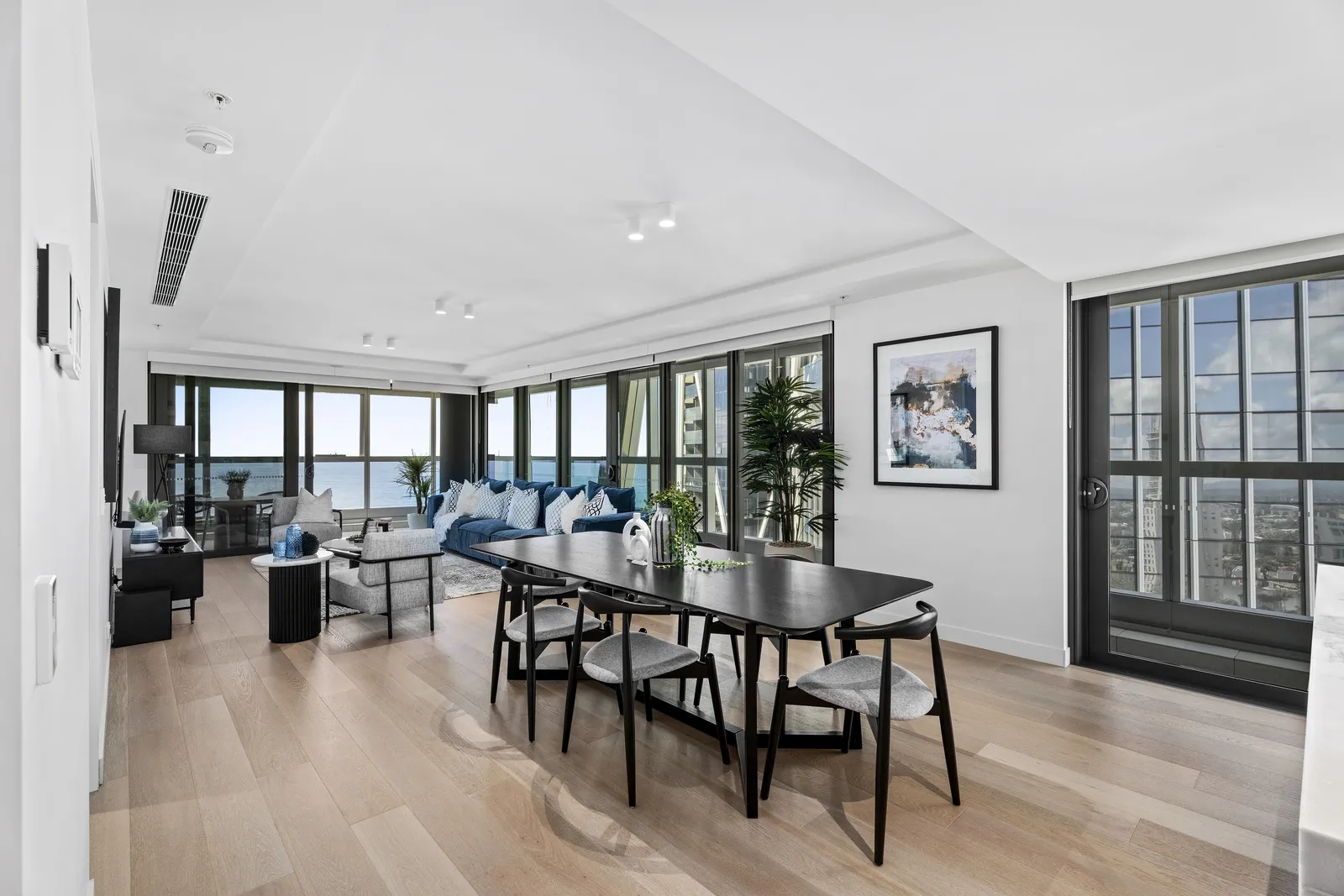 Jewel Residences open-plan living and dining with ocean views, black dining setting and blue sofa