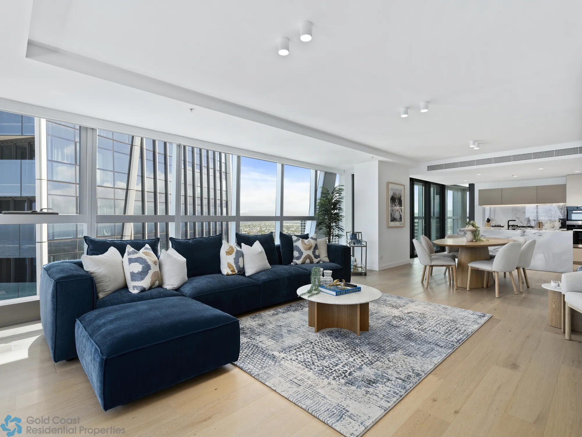 Luxury living area with navy modular sofa, oak coffee table and floor-to-ceiling ocean views