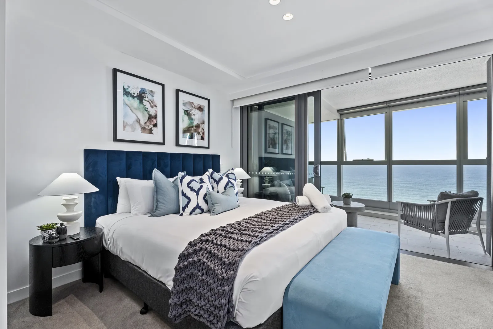 Master suite with navy velvet bedhead, ikat cushions and panoramic ocean views