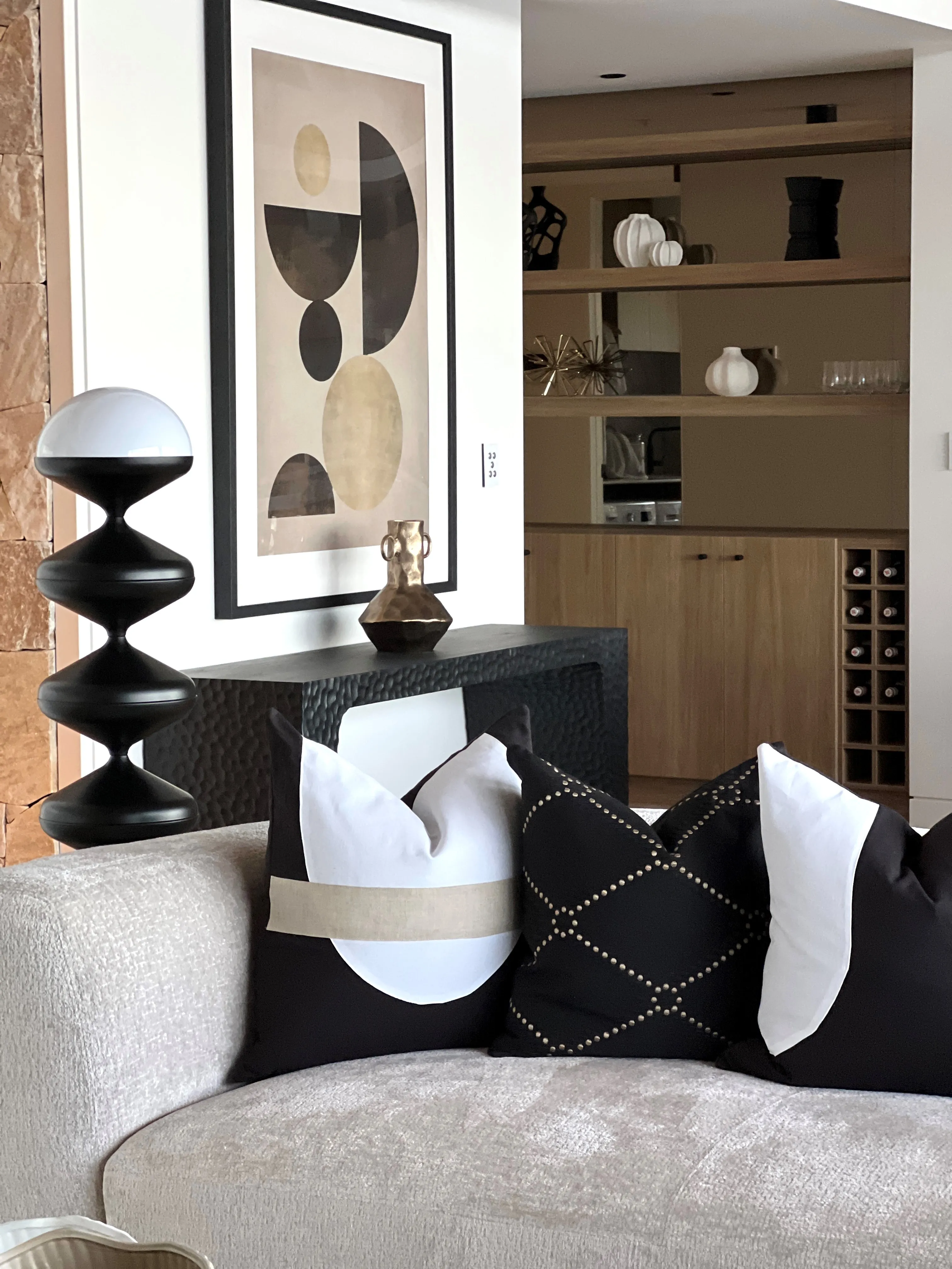 Kings Beach penthouse living area with monochrome cushions, abstract artwork and sandstone feature wall