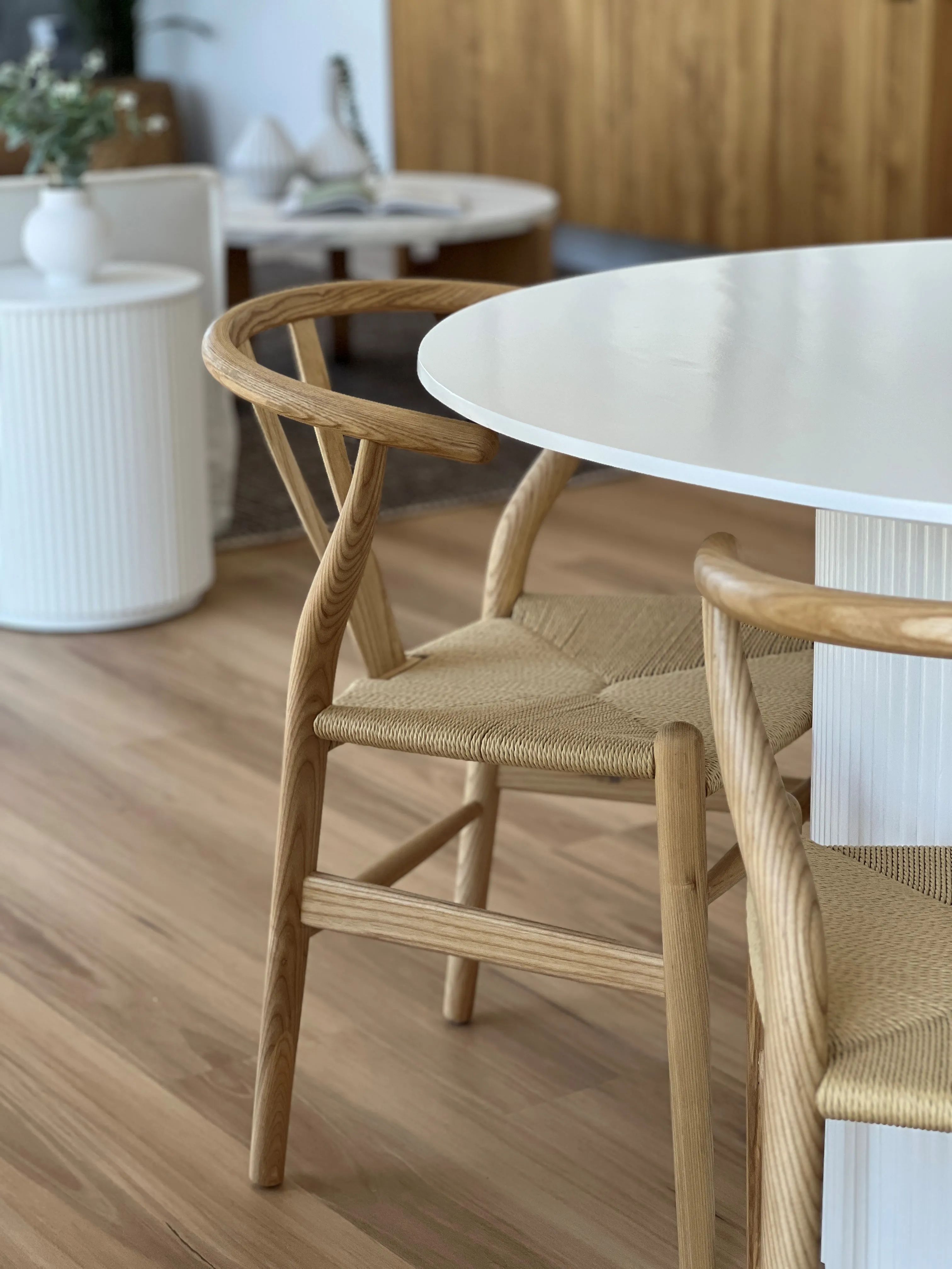 Detail of oak Wishbone chair with woven paper cord seat at white fluted dining table