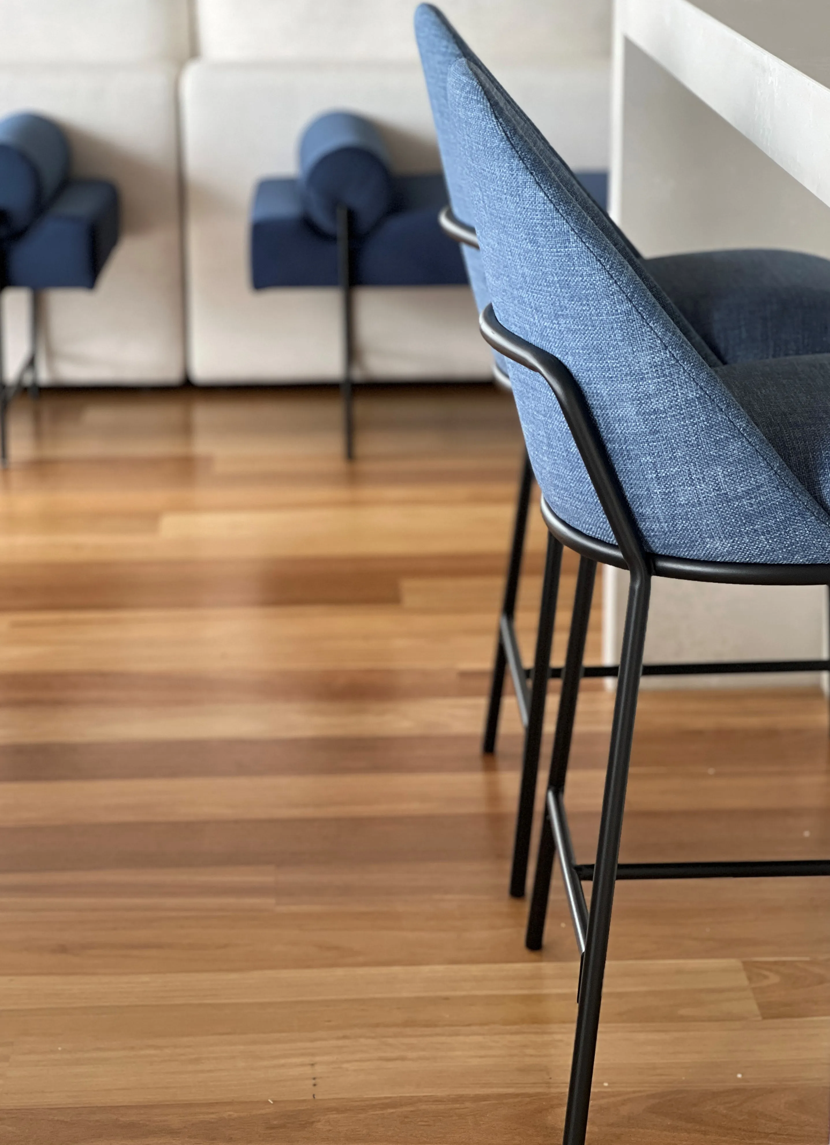 Navy linen bar stools on black metal frames against spotted gum timber flooring