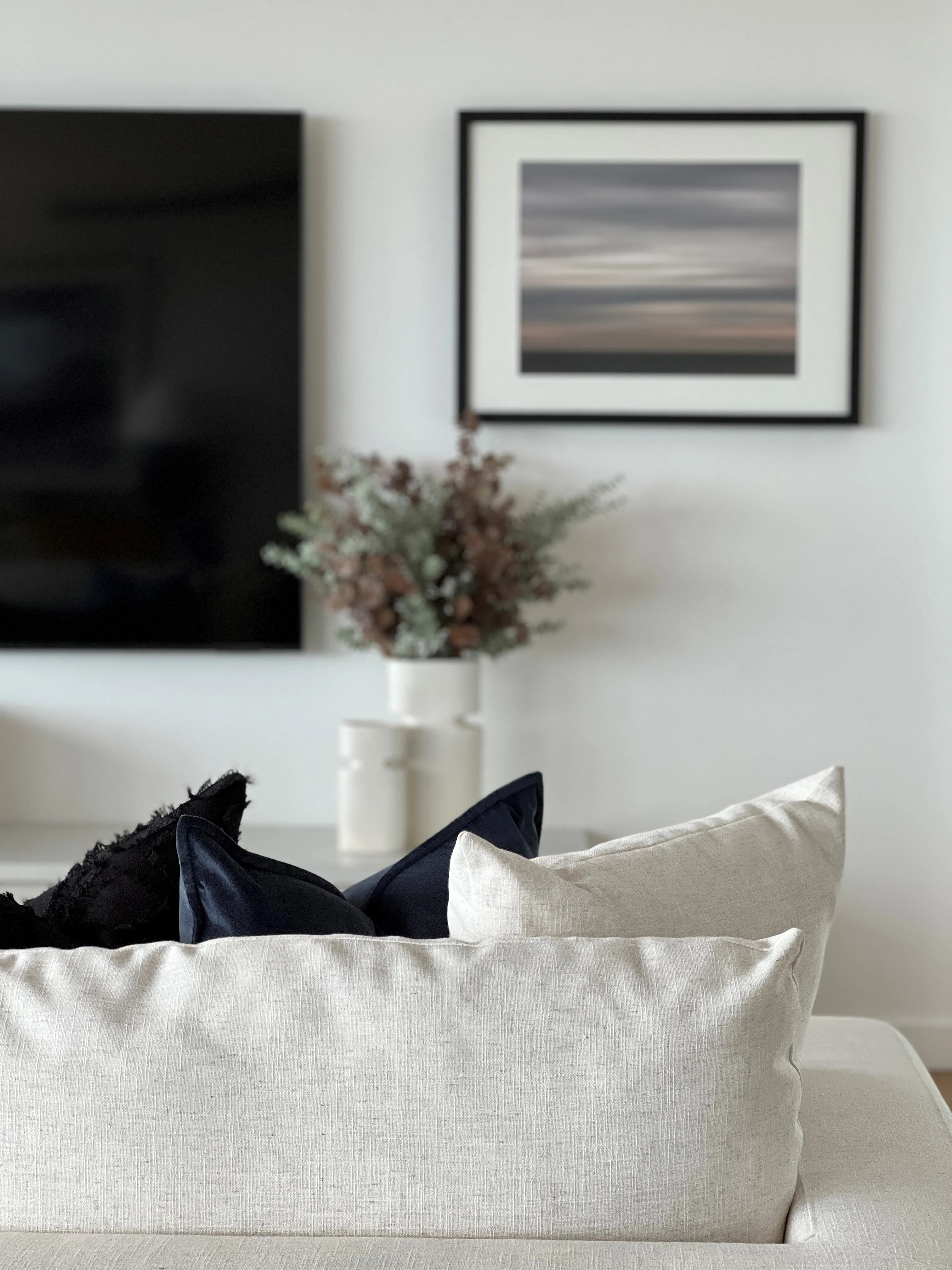 Living room detail with cream linen sofa, navy cushions and abstract seascape print