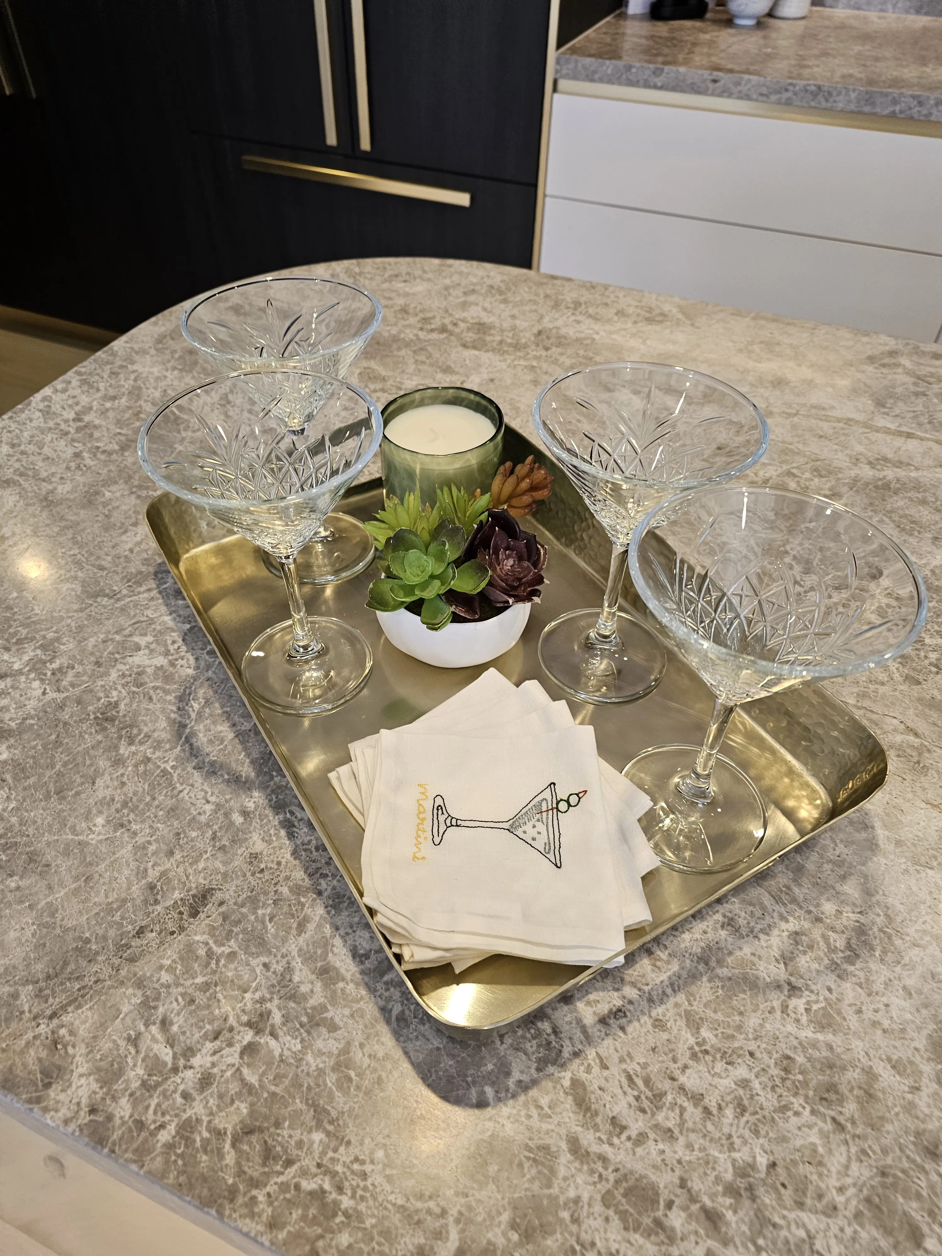 Kitchen island styling with crystal coupe glasses on brass tray and marble surface