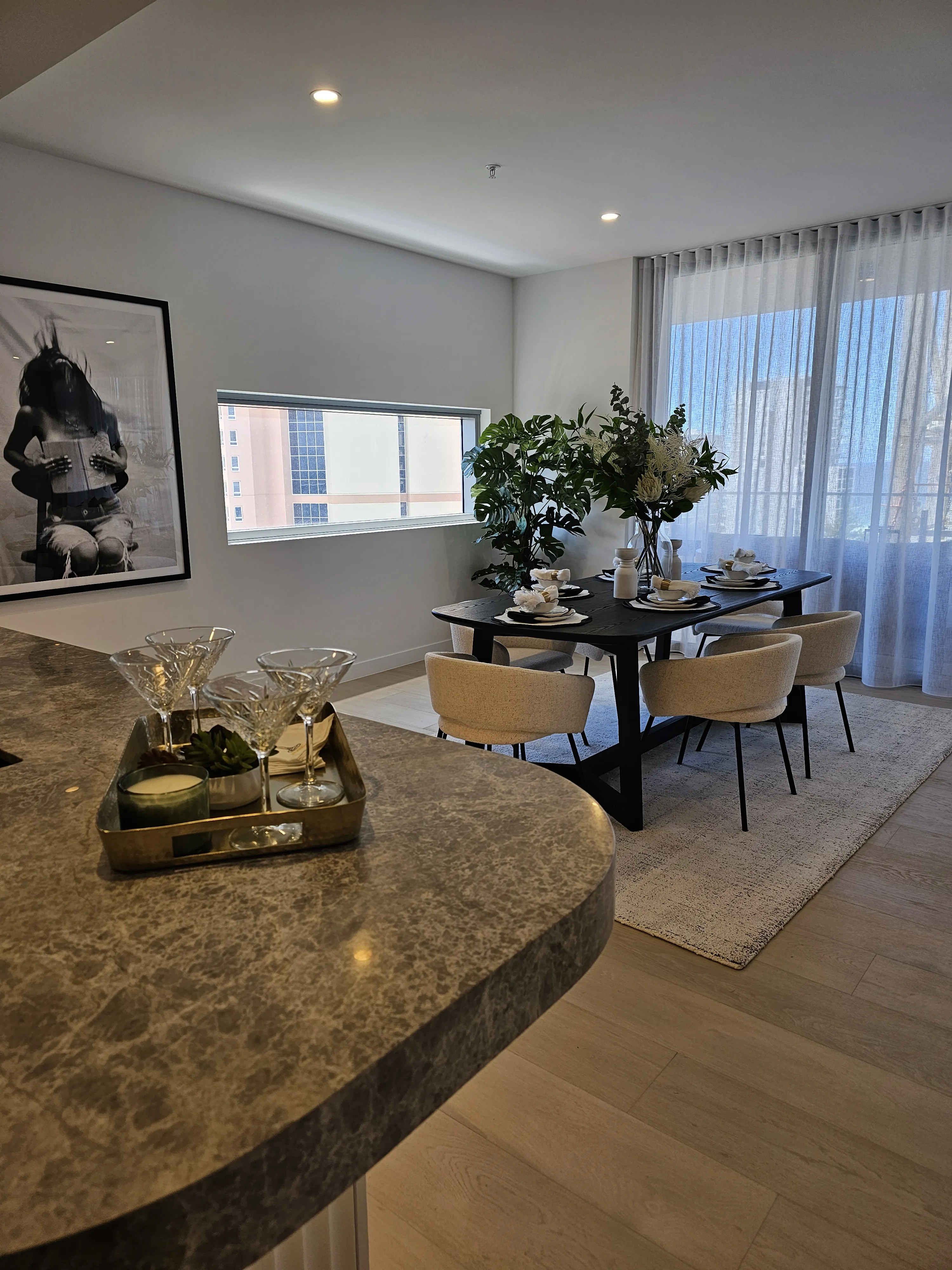 Dining area with taupe chairs, black table and crystal cocktail styling on marble island