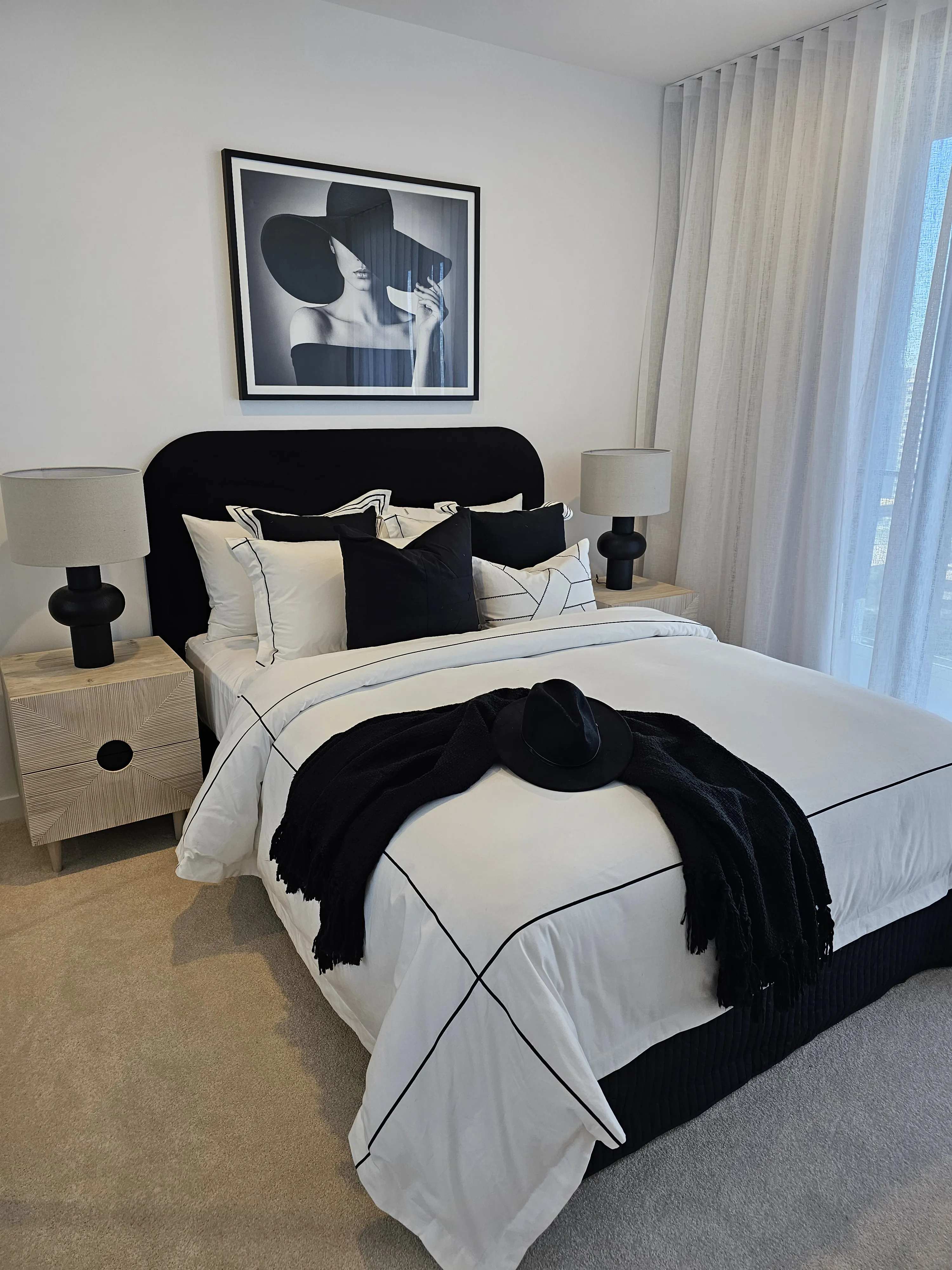 Master bedroom with black velvet bedhead, monochrome linen and fashion photography artwork