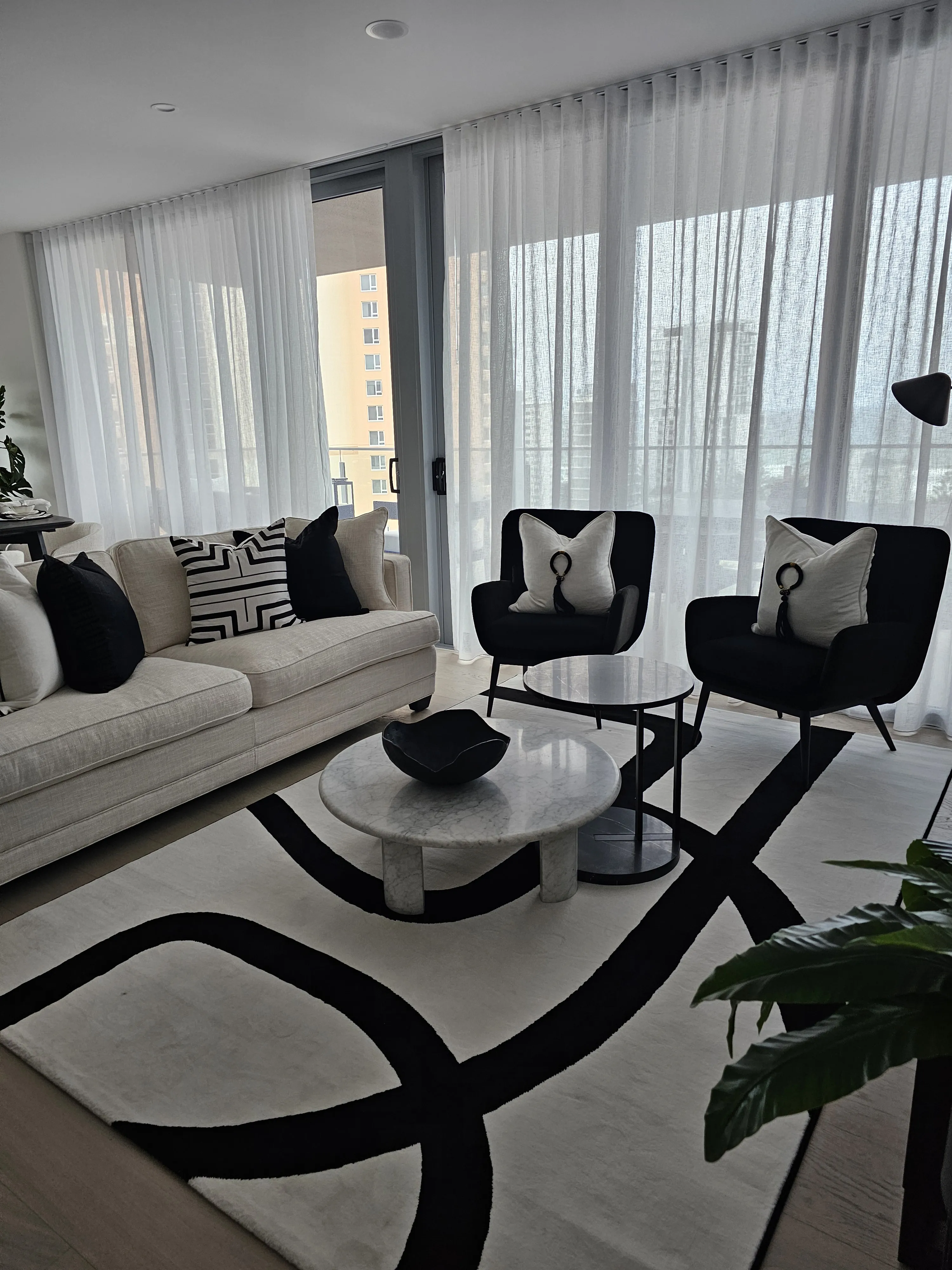 Monochrome living room with cream sofa, black wingback chairs and bold graphic rug