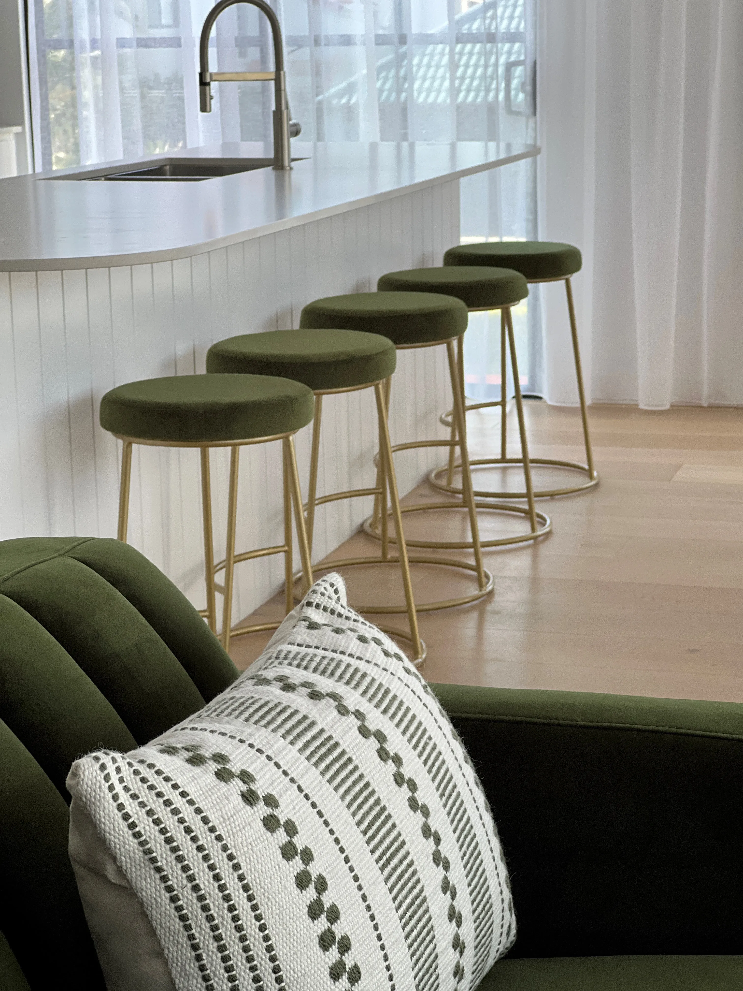 Kitchen bar with olive velvet stools on brass frames and VJ panelled island